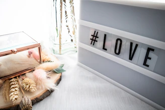 A softly lit photo of a Love Bomb Studio care package featuring fresh flowers, homemade treats, and a handwritten note on a minimalist white background.