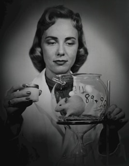 a woman holding a glass with a mouse inside of it