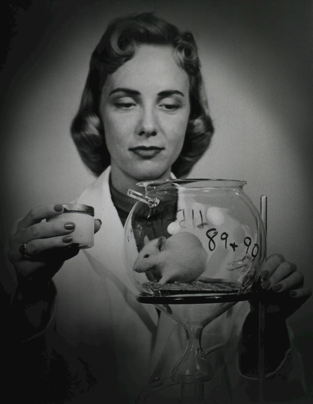 a woman holding a glass with a mouse inside of it