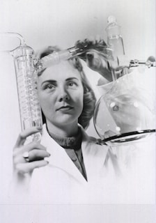 a black and white photo of a woman holding a flask