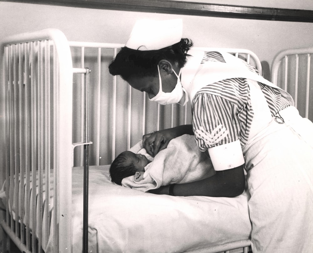 a nurse is holding a baby in a crib