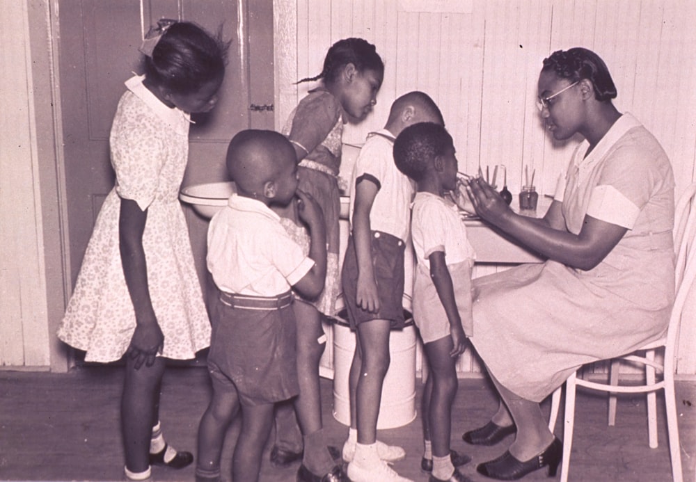 a black and white photo of a woman teaching children