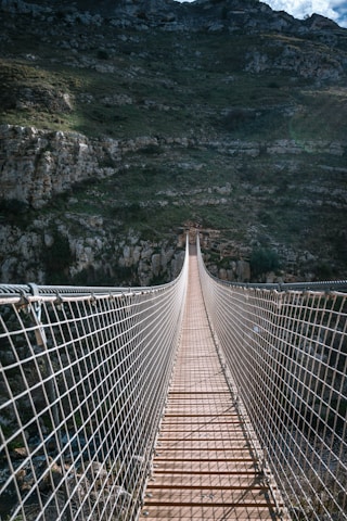 a very long suspension bridge with a mountain in the background