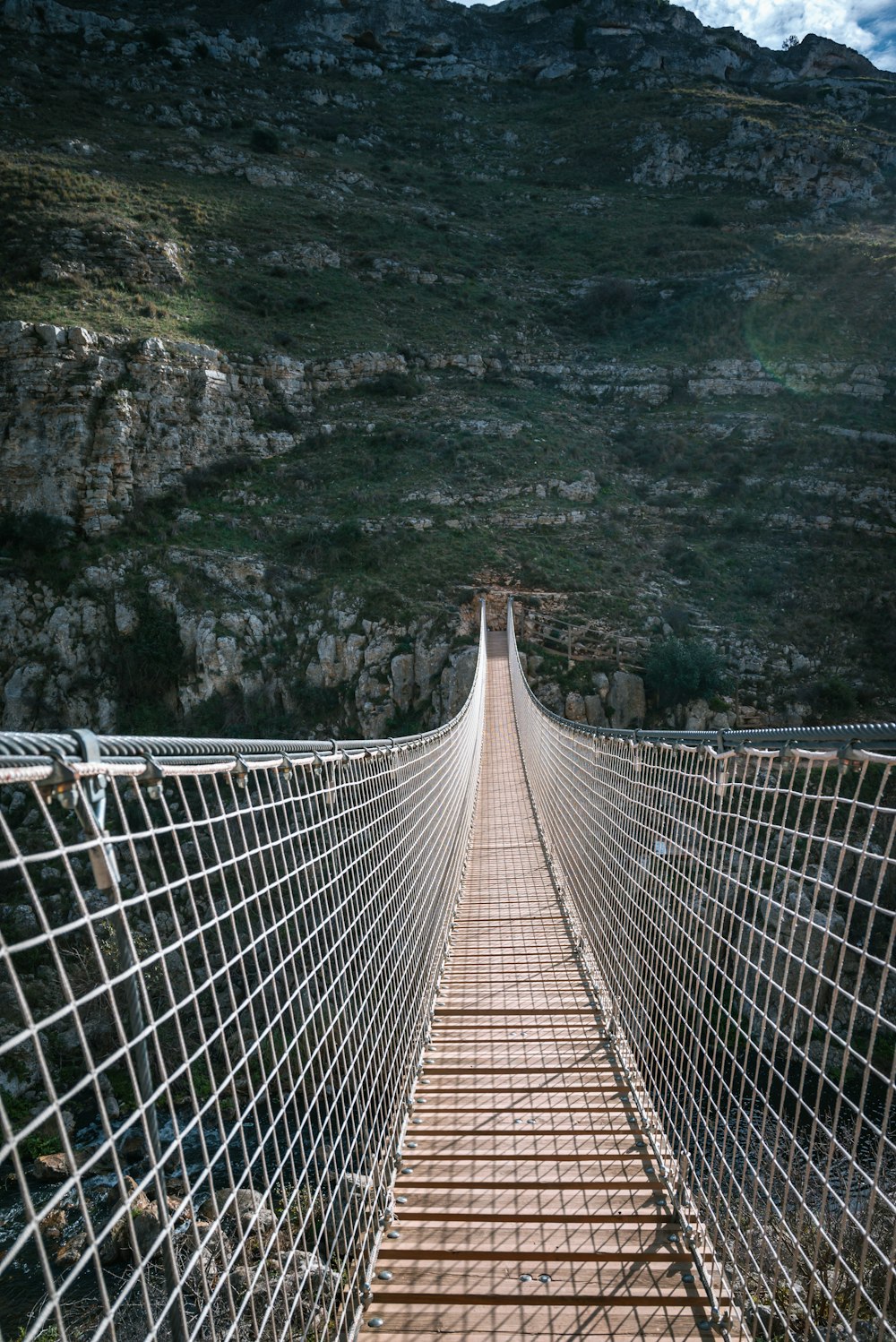 a very long suspension bridge with a mountain in the background