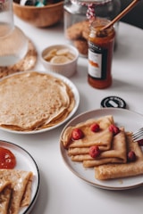 An inviting setup of a crepe bar with various toppings and a chef preparing crepes.