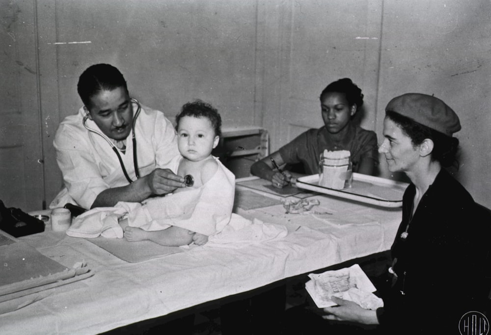 um grupo de pessoas sentadas ao redor de uma mesa com um bebê
