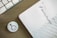 A wooden desk features a corner of a keyboard on the left and a planner on the right. The planner is opened to a page showing Wednesday the 21st and Thursday the 22nd with 'Hashtag Campaign' handwritten under Wednesday. A small circular badge with a smiling face icon lies near the planner.