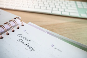 a notepad with a spiral - bound notebook on it next to a keyboard