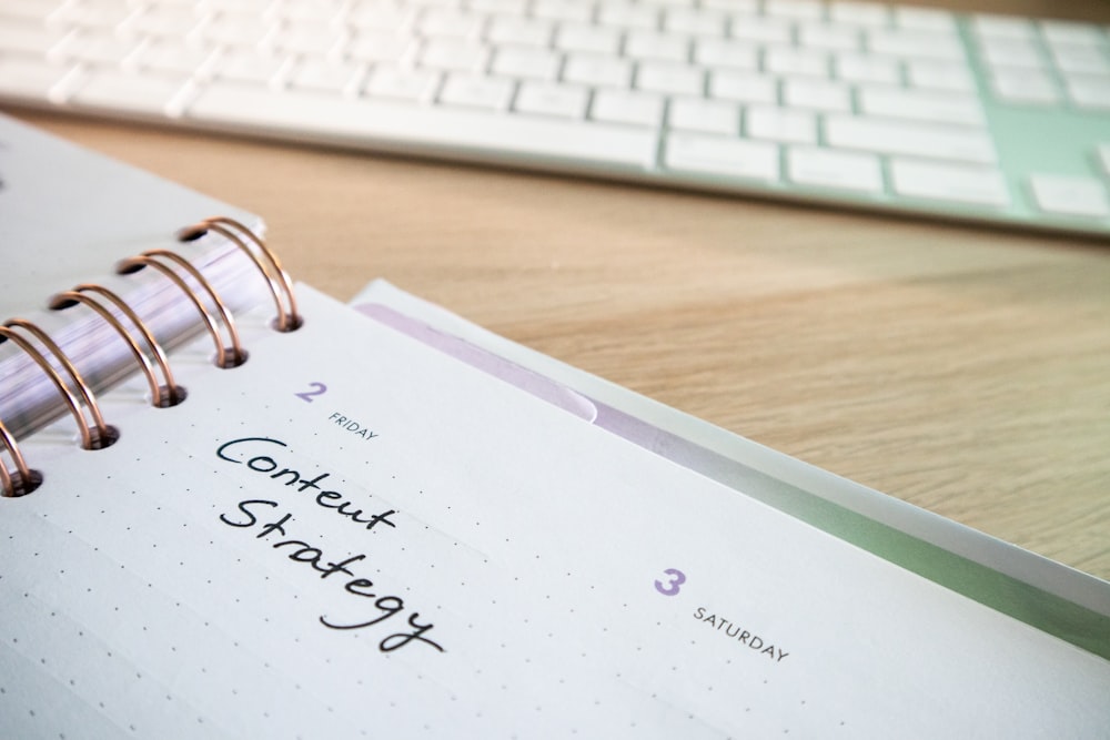 a notepad with a spiral - bound notebook on it next to a keyboard