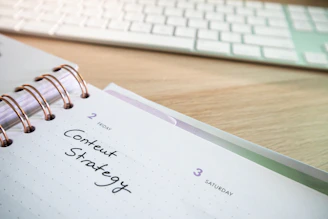 a notepad with a spiral - bound notebook on it next to a keyboard