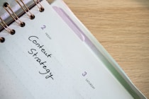 a spiral notebook with a notepad and pen on top of it