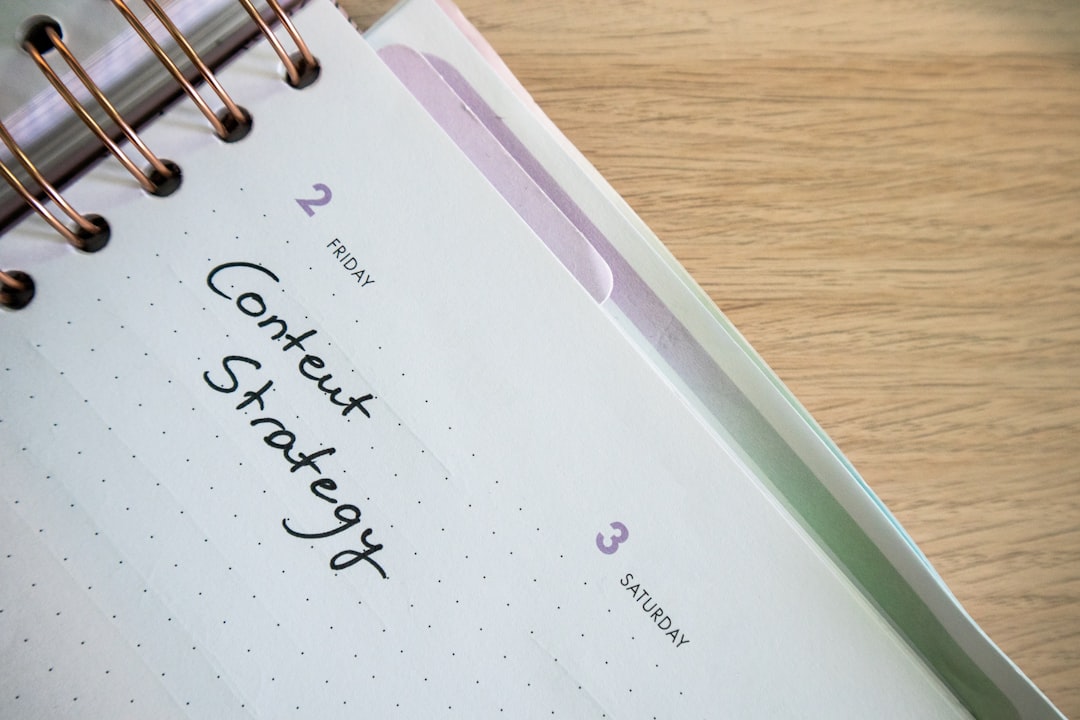 a spiral notebook with a notepad and pen on top of it, Desk with a planner with the words Content Strategy on it