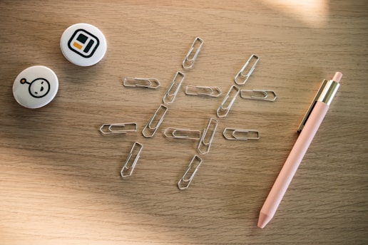 a pen and some paper clips on a table