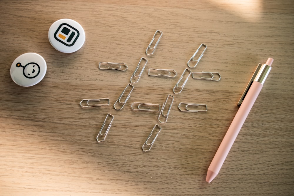 a pen and some paper clips on a table