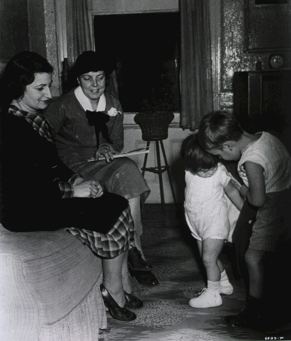 a black and white photo of a woman and two children