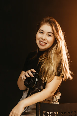 A candid portrait of the photographer in natural light, holding a camera with a gentle smile.