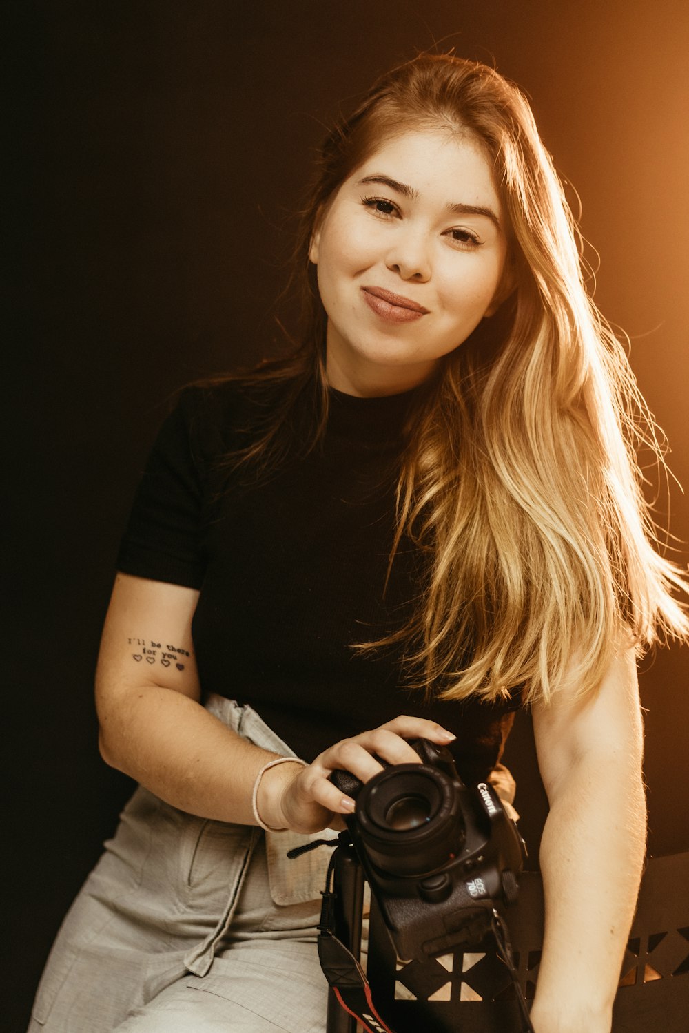 a woman holding a camera in front of a black background