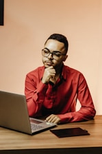 A calm person sitting at a desk with a laptop, looking hopeful while planning next career steps.
