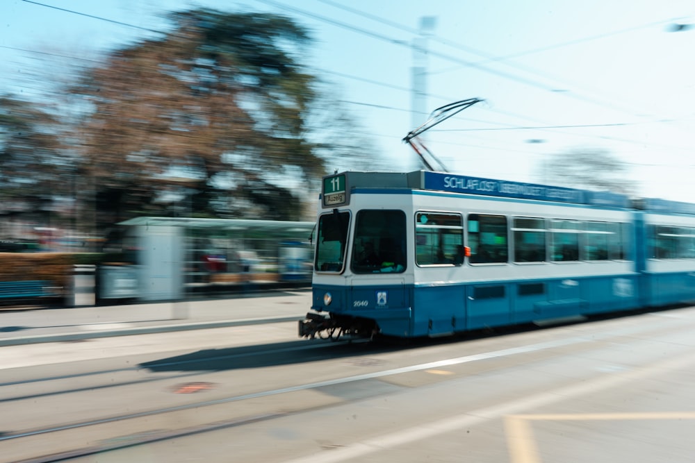 a blue and white tram traveling down a street