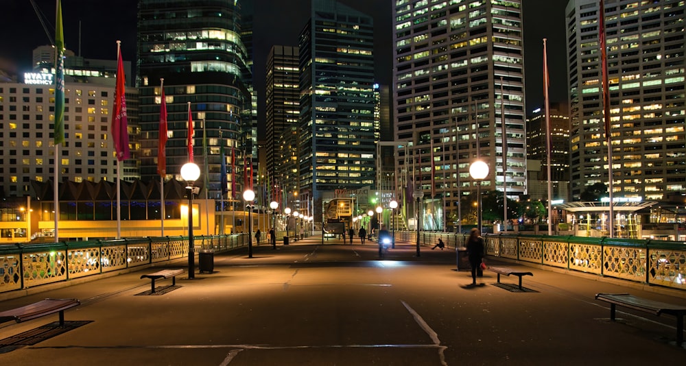 Una persona parada en un puente en una ciudad por la noche