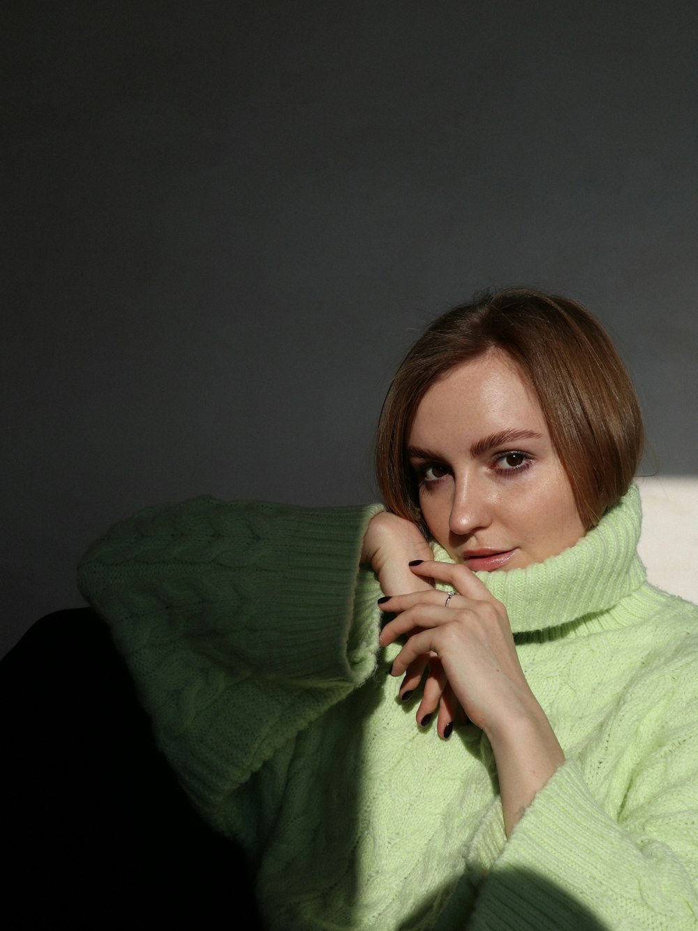 a woman in a green sweater poses for a picture