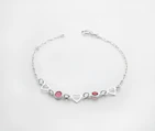 a silver bracelet with hearts and two red stones