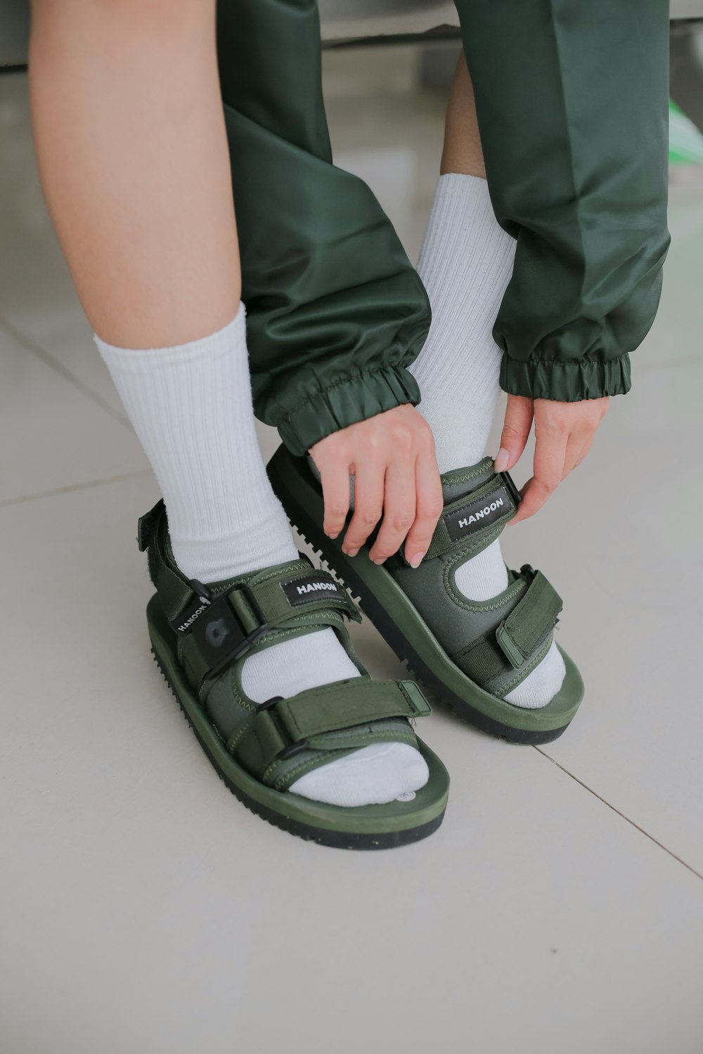 a person putting on a pair of green sandals