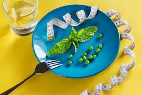 a blue plate topped with green vegetables and measuring tape