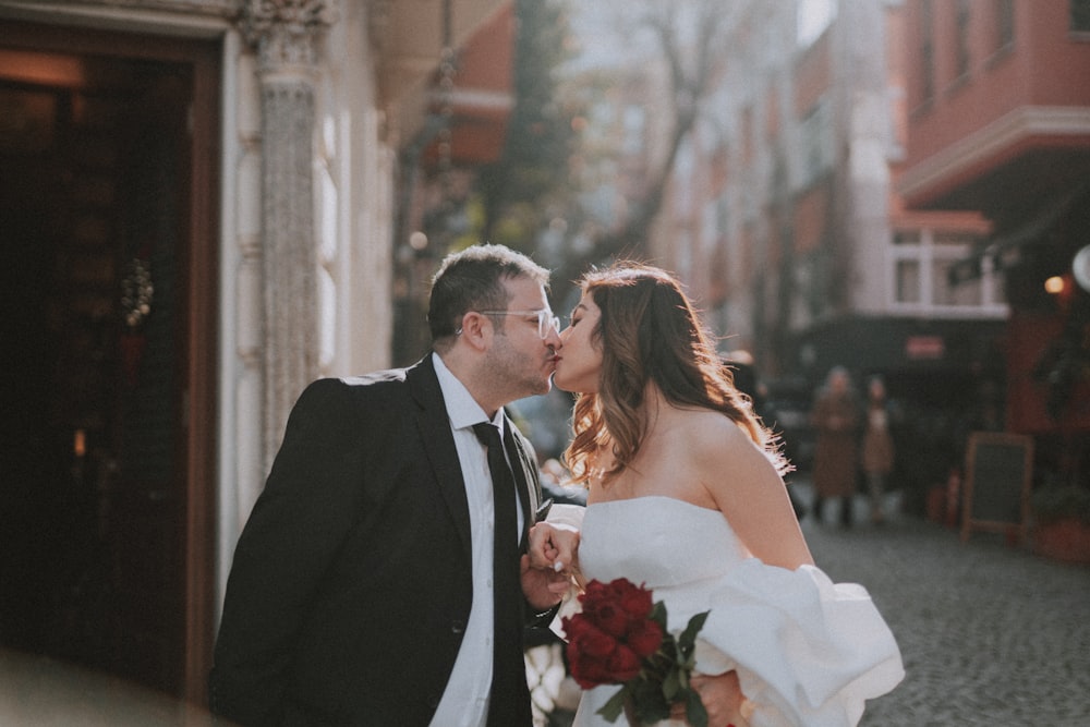 a bride and groom kissing in front of a building