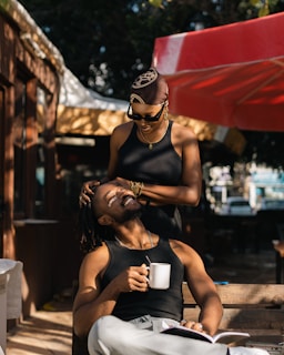 A man and a woman laughing together at a café terrace.