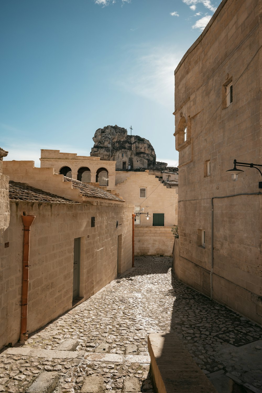 a cobblestone street with a stone building in the background