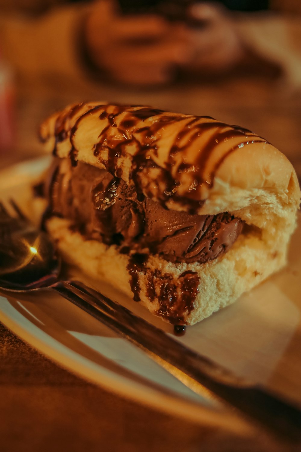 Un sándwich de helado de chocolate en un plato con una cuchara