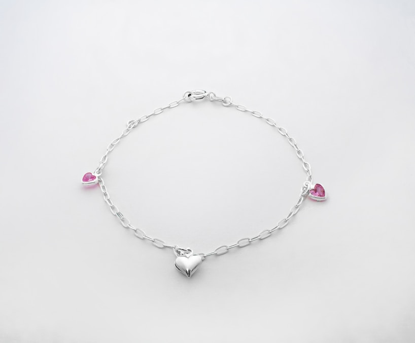 a silver bracelet with hearts and pink stones
