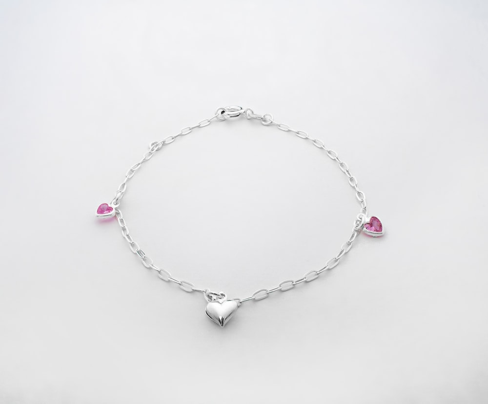 a silver bracelet with hearts and pink stones