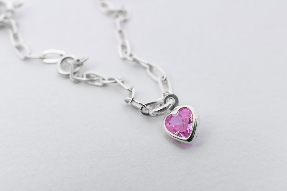 a pink heart shaped pendant on a silver chain