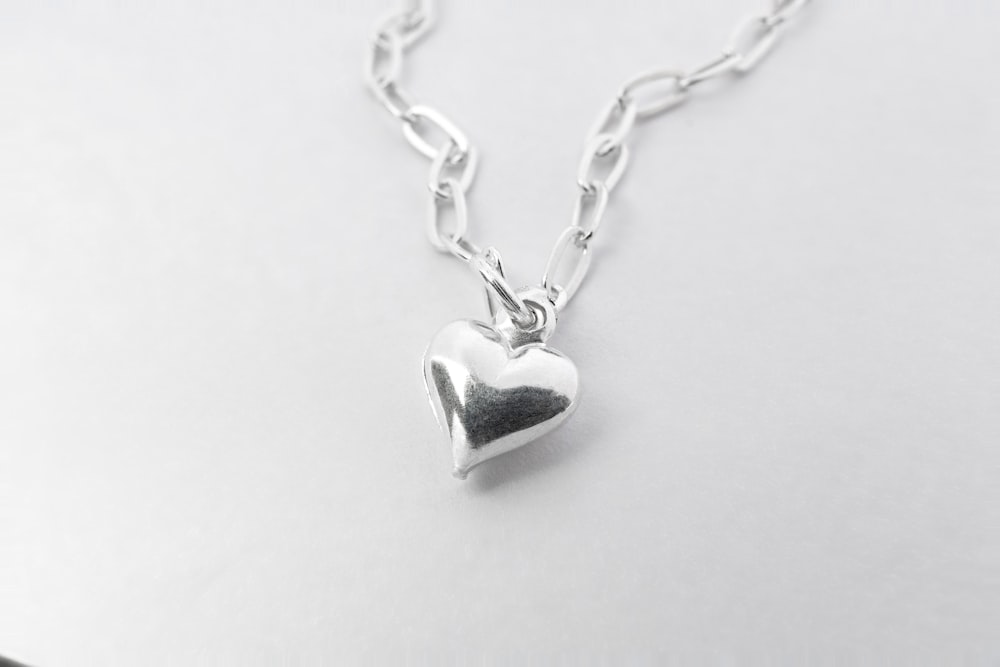 a silver heart necklace on a white surface