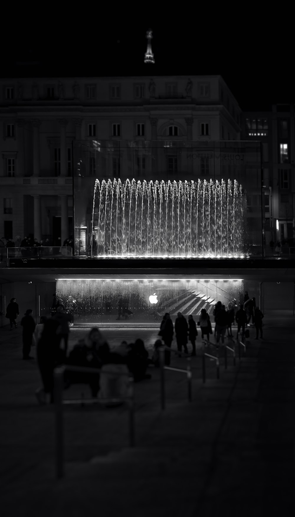 a black and white photo of a fountain at night