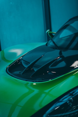 Close-up of a sleek car hood glowing under neon pink and blue lights at an orldriftwave event.