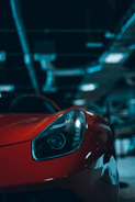 Close-up of a sleek supercar's headlight glowing under garage lights.