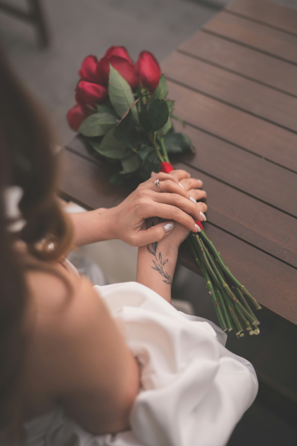 a woman sitting at a table with a bouquet of roses
