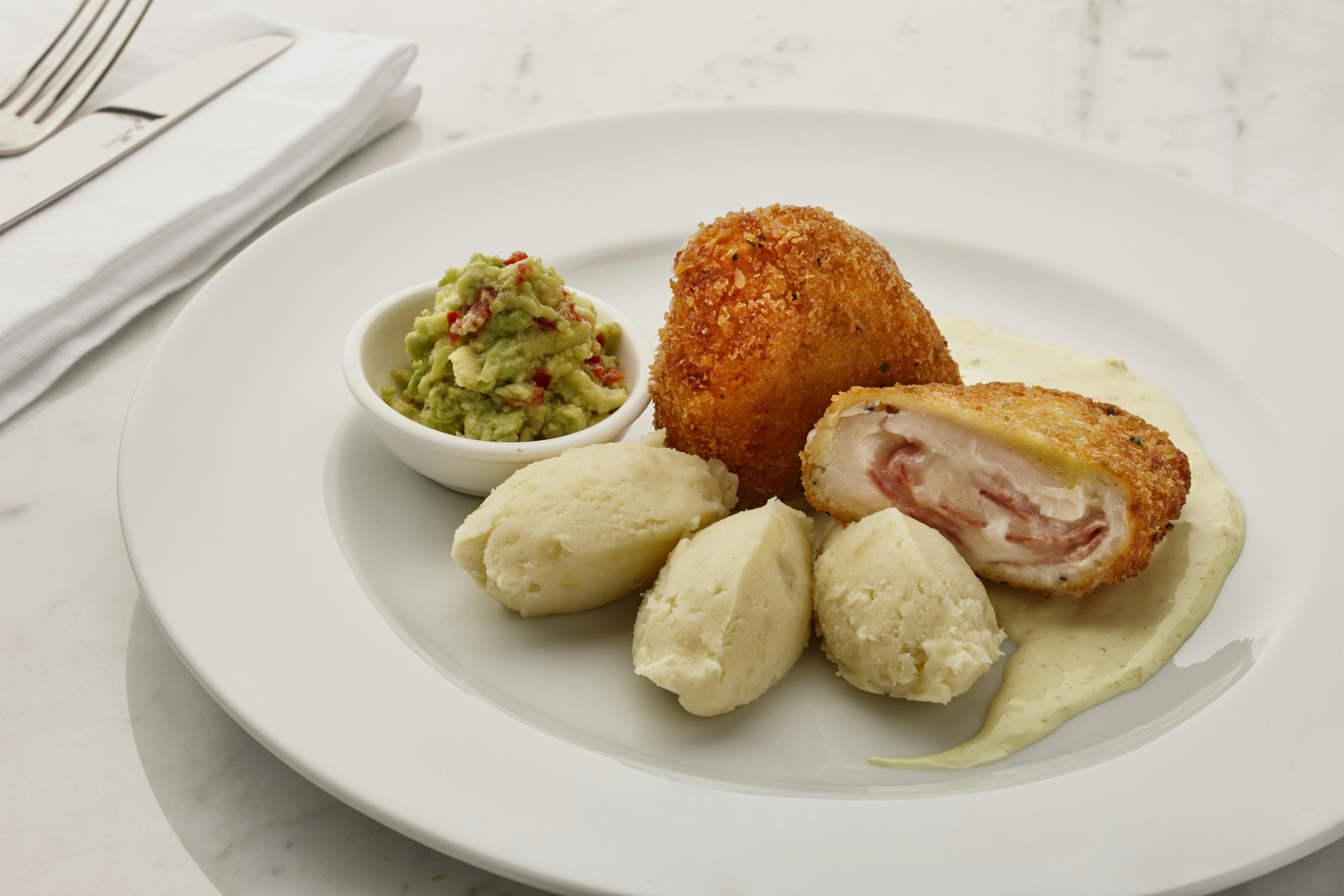 um prato branco coberto com comida ao lado de uma tigela de guacamole