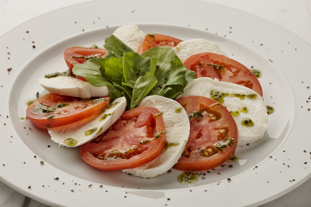 a white plate topped with sliced tomatoes and mozzarella