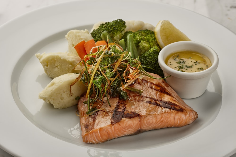 a white plate topped with fish and vegetables