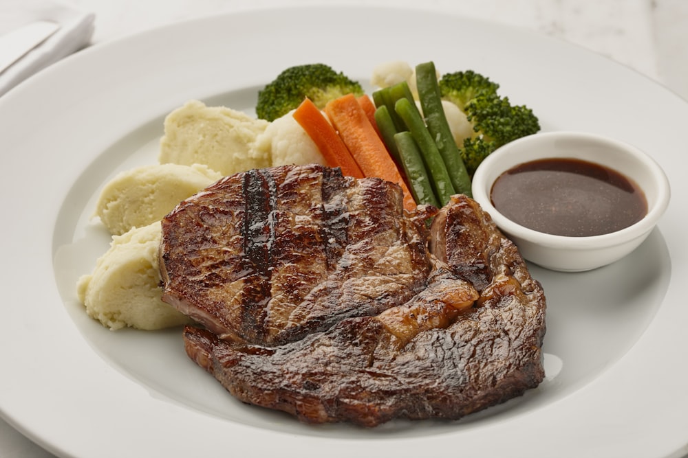 une assiette blanche garnie de viande et de légumes