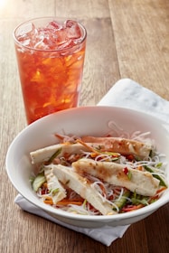 Artfully plated vermicelli bowl with grilled meats and fresh vegetables.