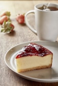 a piece of cheesecake on a plate next to a cup of coffee
