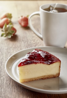 a piece of cheesecake on a plate next to a cup of coffee
