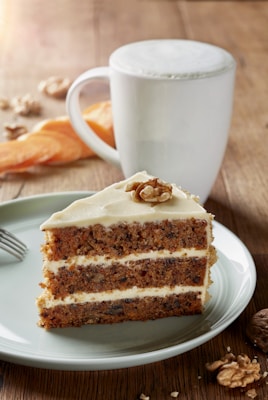 A close-up of a rustic carrot cake topped with cream cheese frosting and a sprinkle of walnuts.