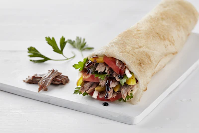 A chef preparing a vibrant, healthy wrap with fresh ingredients.
