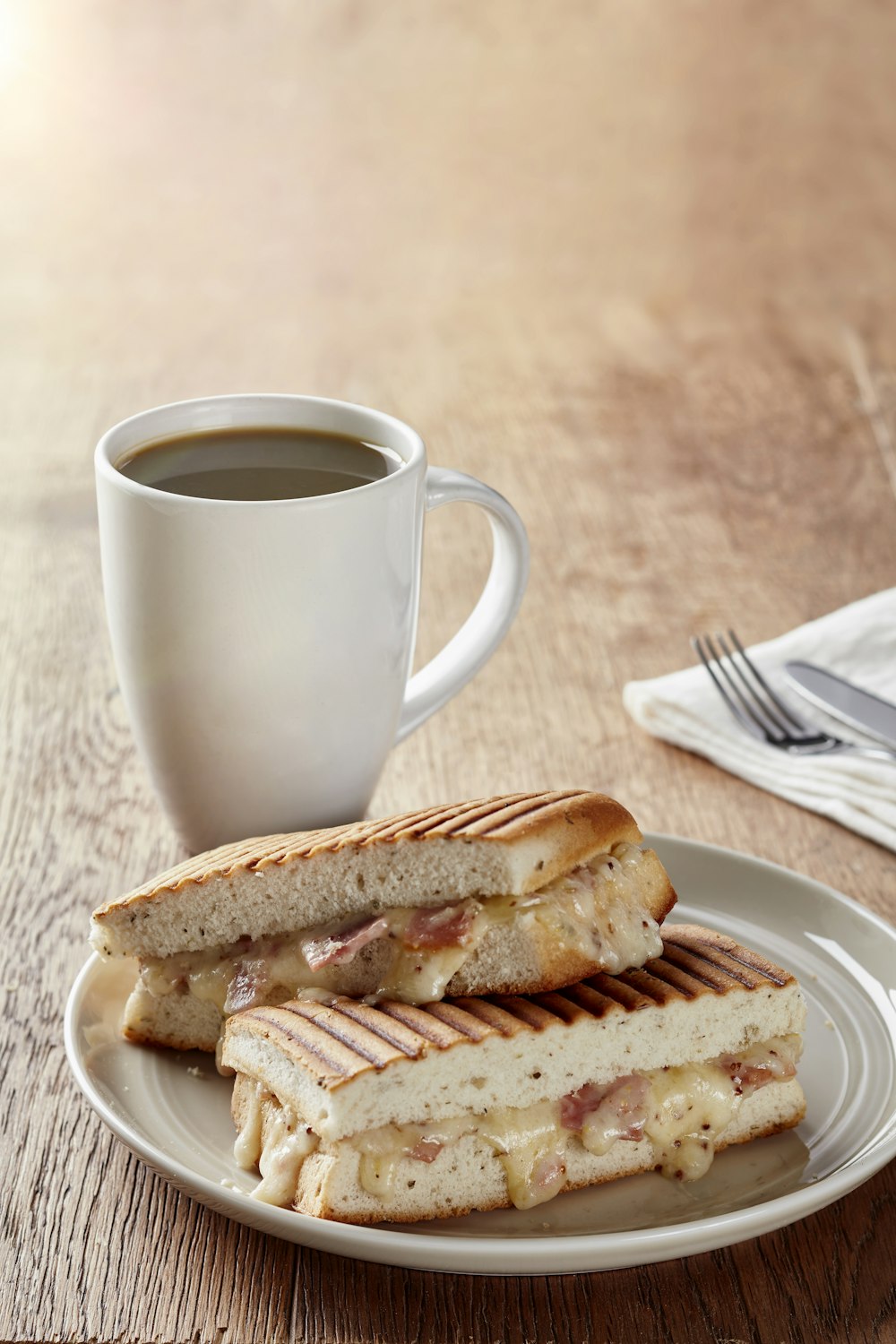 a plate with a sandwich and a cup of coffee